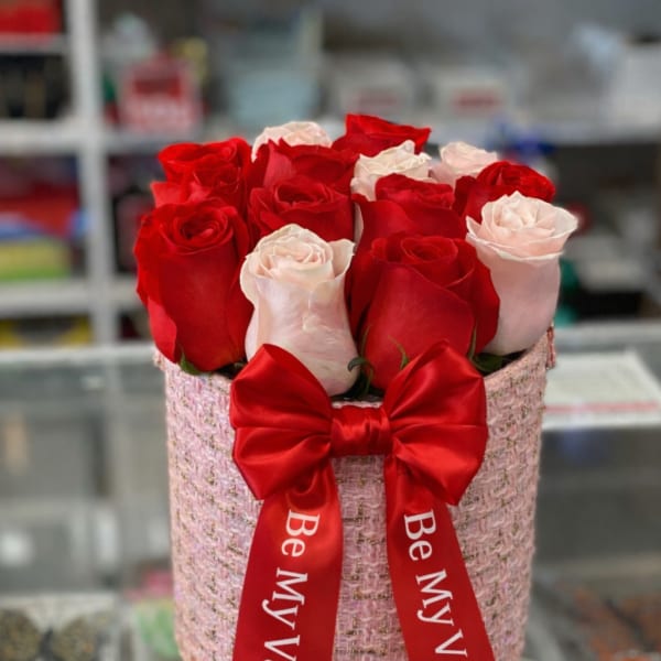 Red and pale pink roses in a pink gift box with a red ribbon