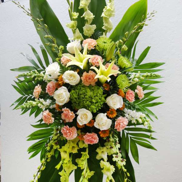 Large standing floral spray with white lilies, roses, and peach carnations