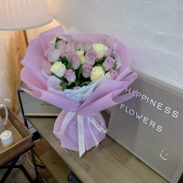 Bouquet of pale pink and cream roses wrapped in lavender paper