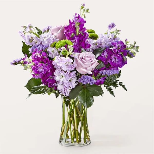 Purple and lavender bouquet with roses in a clear glass vase