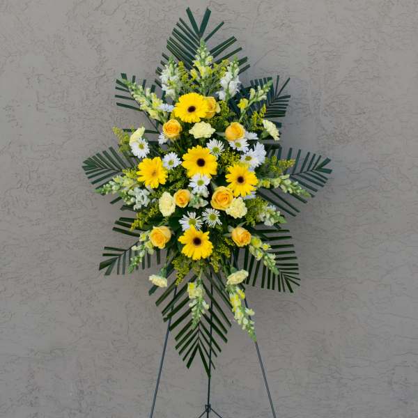 Standing floral spray with yellow and white flowers on an easel