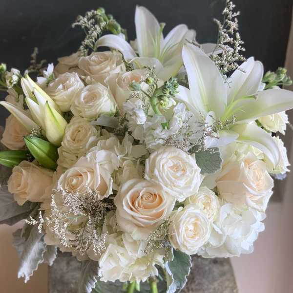 White roses and lilies arranged in a glass vase