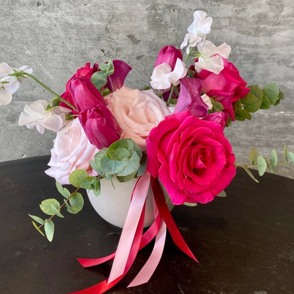 Pink and white rose bouquet in a white vase with ribbon