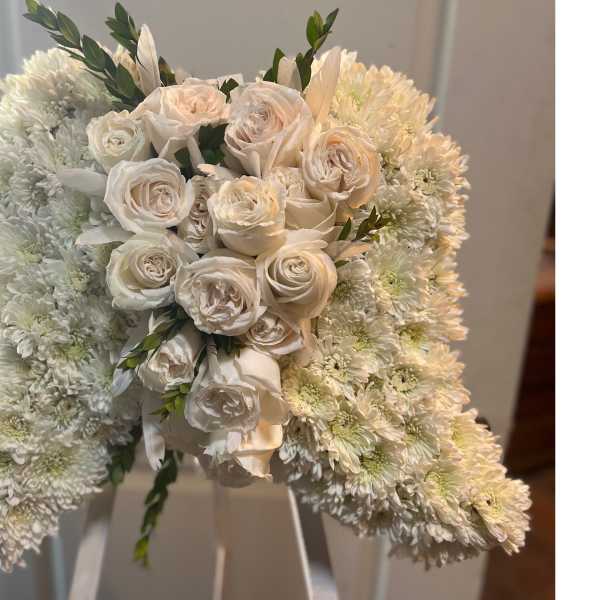 White bell-shaped floral arrangement of chrysanthemums with clustered ivory roses in the center