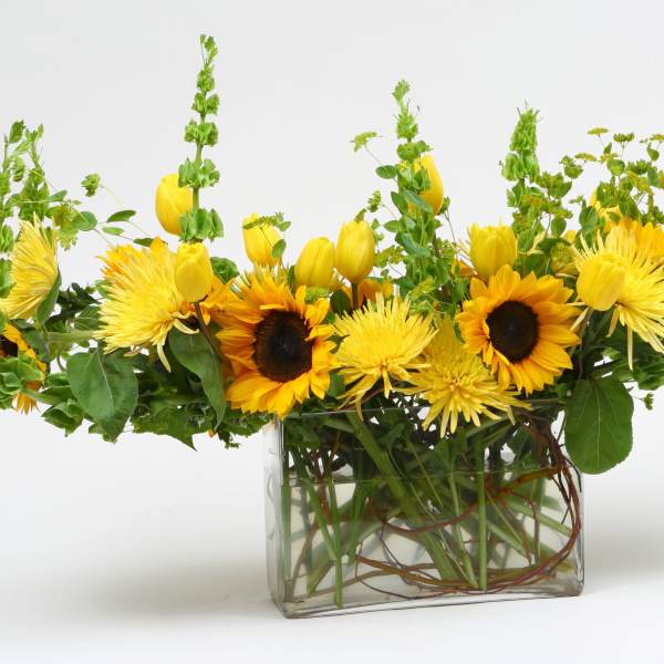Yellow sunflowers and tulips in a clear glass vase