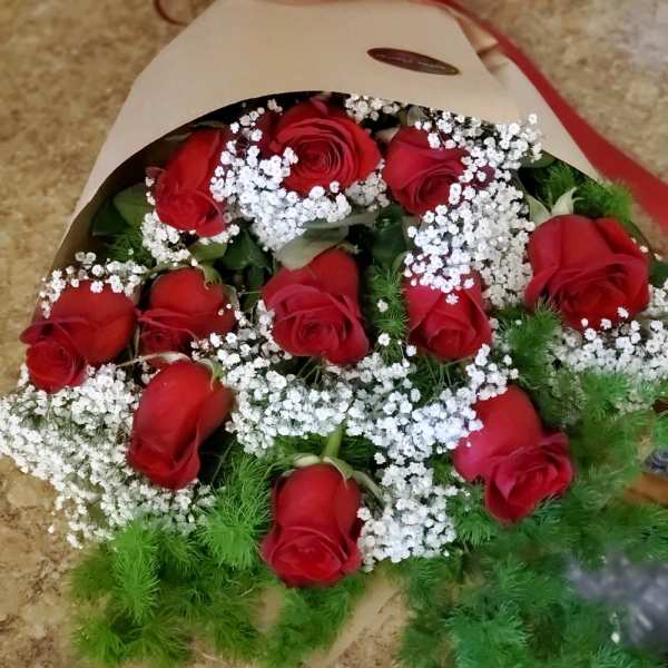 Bouquet of red roses with white baby's breath in kraft paper and a red ribbon