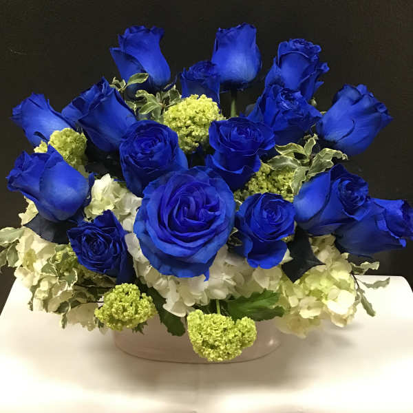 Blue roses and white hydrangeas arranged in a low white container