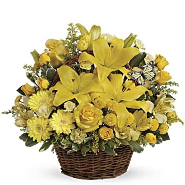 Basket arrangement of yellow lilies, roses, daisies, and mixed blooms with a small decorative butterfly accent