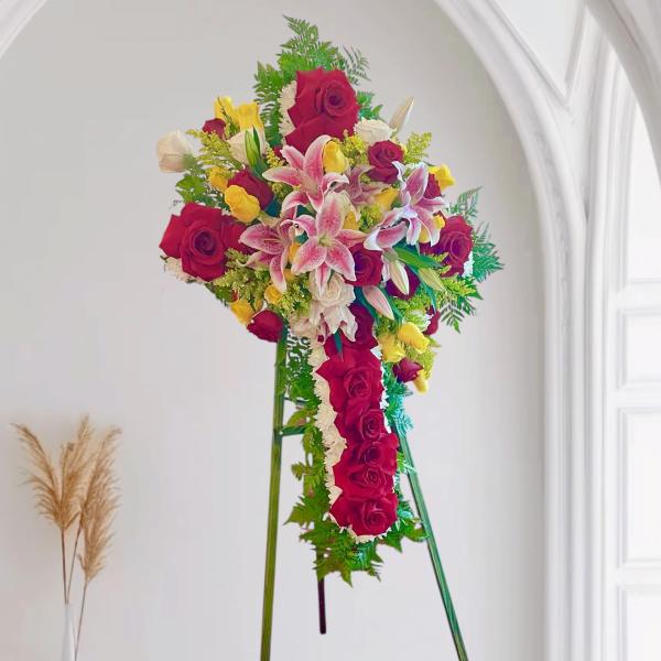 Standing floral spray of red roses, pink lilies, and yellow blooms on an easel