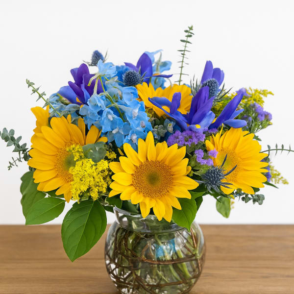 Yellow sunflowers and blue flowers in a glass vase