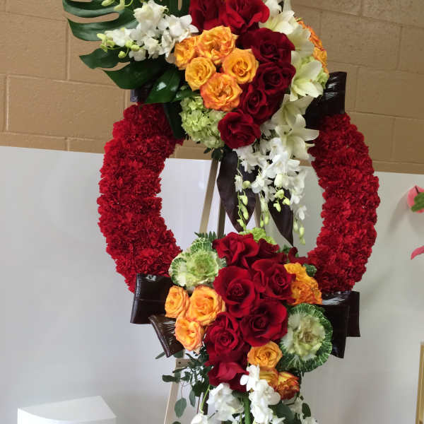 Large floral standing wreath with red, orange, and white flowers