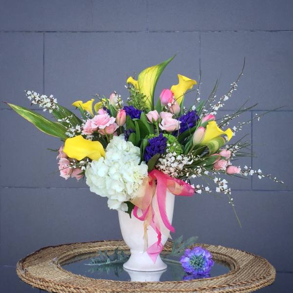 Colorful floral arrangement in a white vase with pink, yellow, purple, and white blooms