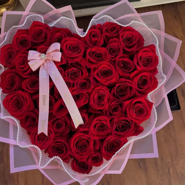 Heart-shaped bouquet of red roses with pink ribbon wrapping