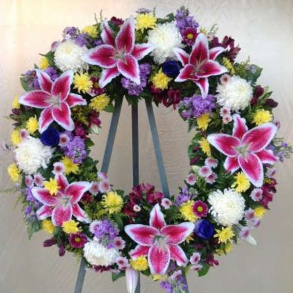 Large floral wreath on an easel with pink lilies and mixed blooms