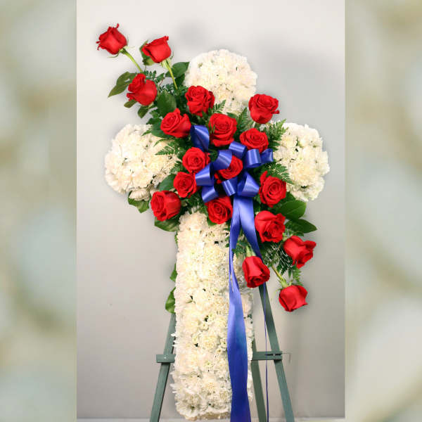 Standing floral cross of white flowers and red roses with a blue ribbon