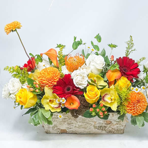 Mixed bouquet in a rustic rectangular wooden container with orange, yellow, red, and white flowers