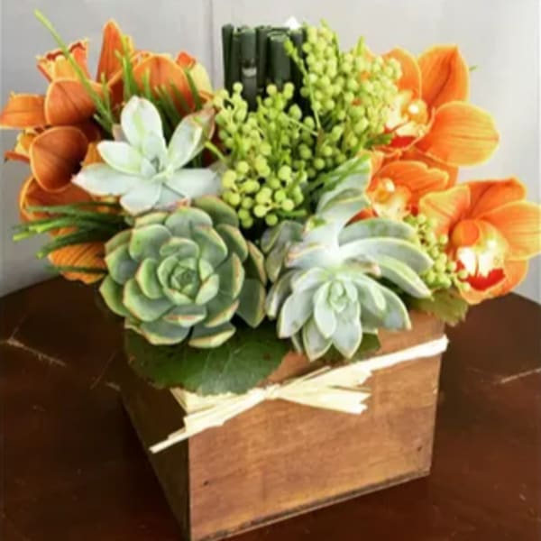 Orange flowers and succulents arranged in a wooden box with a ribbon
