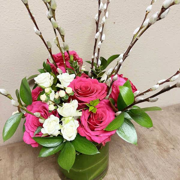 Pink and white roses in a green vase with pussy willow branches
