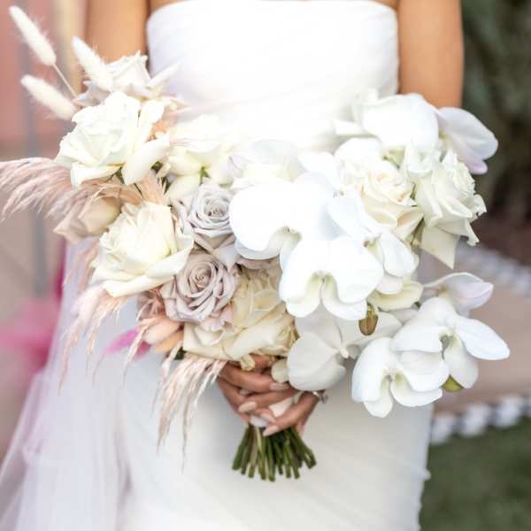 Bride holding a white bouquet with roses and orchids