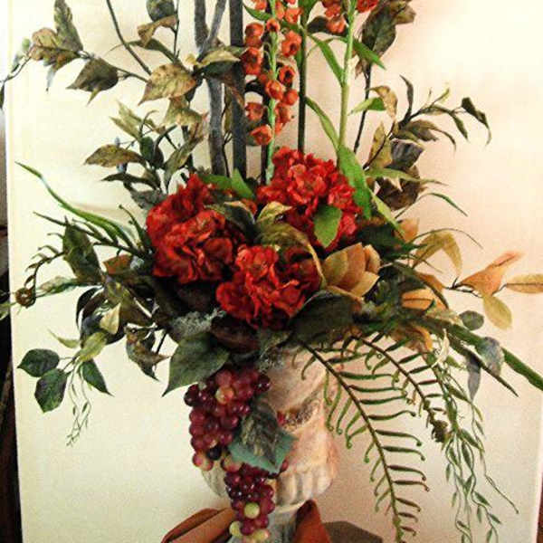 Tall floral arrangement with red blooms and orange spray flowers in a vase