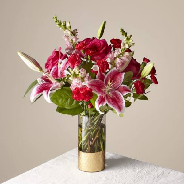 Pink lilies and red roses arranged in a glass vase