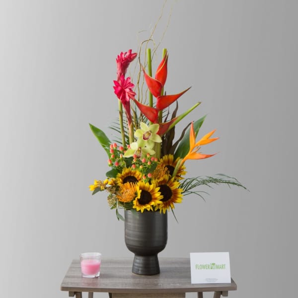 Tall tropical bouquet with sunflowers and orange bird-of-paradise in a dark vase
