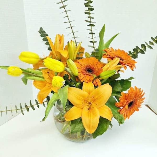 Yellow and orange flower arrangement in a clear glass vase