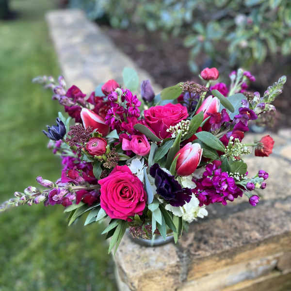 Bouquet of hot pink roses and purple flowers in a low vase