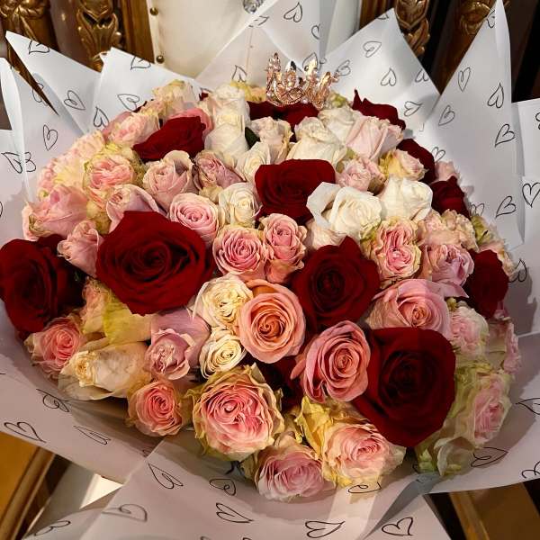 Large bouquet of red, pink, and white roses wrapped in heart-patterned paper