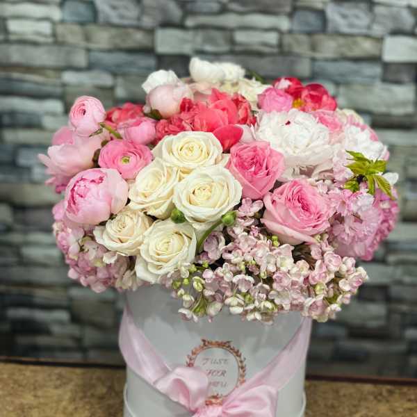Pink and white roses in a white hat box with a pink ribbon