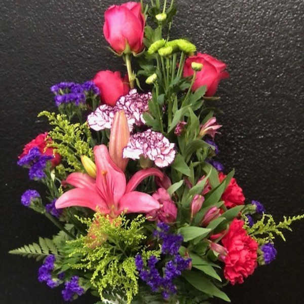 Tall mixed bouquet in a white vase with pink roses, lilies, and purple accents