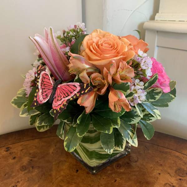 Mixed bouquet in a square glass vase with a butterfly decoration