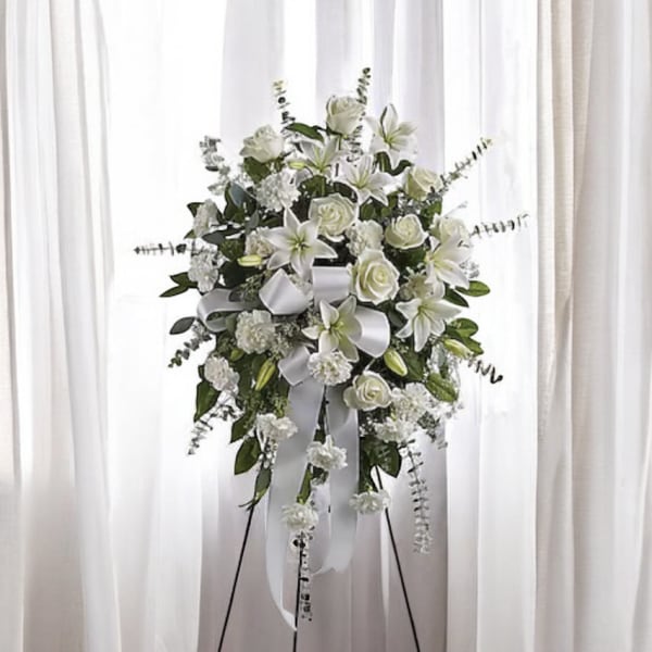 White floral standing spray with lilies, roses, and ribbon