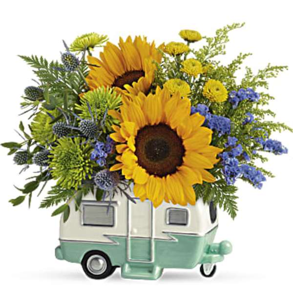 Sunflowers and blue flowers arranged in a small camper-shaped container