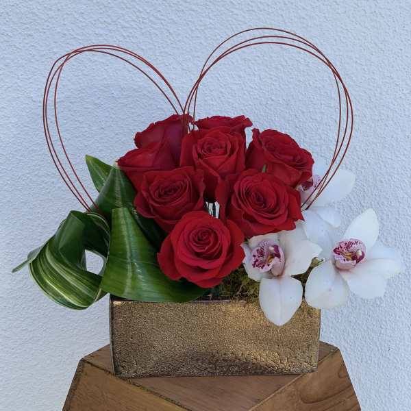 Red roses and white orchids in a gold box with wire heart handles