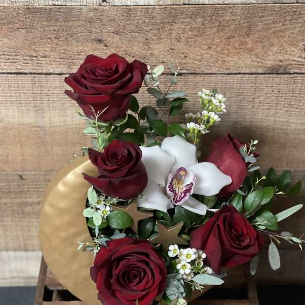 Bouquet of red roses and white orchids with greenery in a gold box