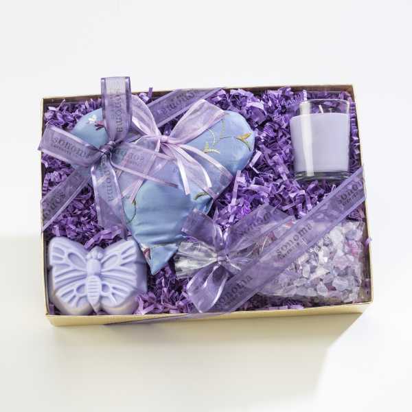 Lavender-themed gift box with heart sachet, candle, butterfly soap, and bath salts on purple fill
