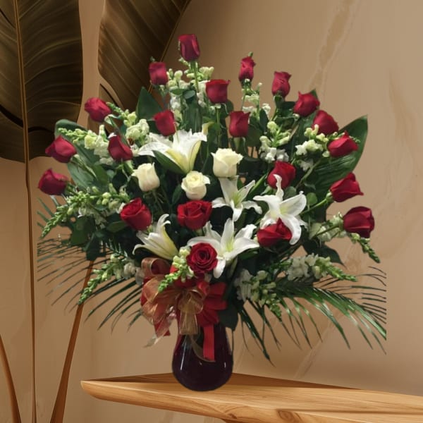 Tall bouquet of red and white roses with lilies in a dark vase
