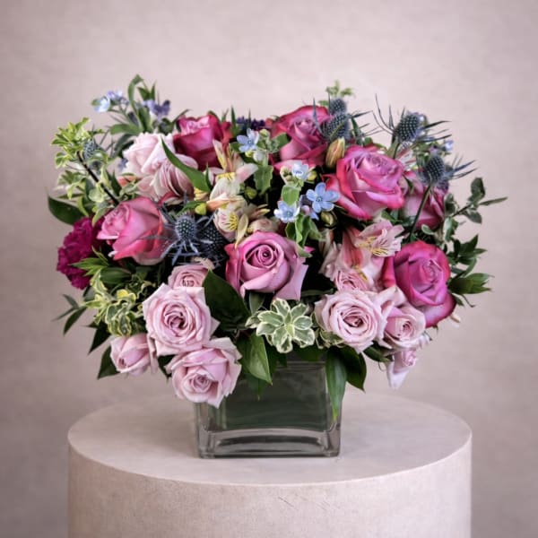 Pink and lavender rose arrangement in a square glass vase