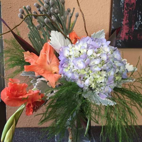 Bouquet of lavender hydrangea and orange lilies in a glass vase