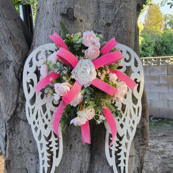 Floral angel wings with pink and white roses on a tree trunk