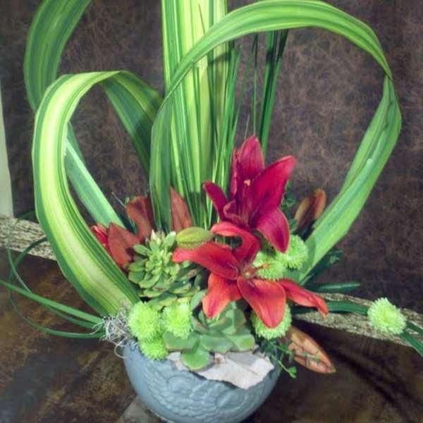 Tropical floral arrangement with red lilies in a blue bowl