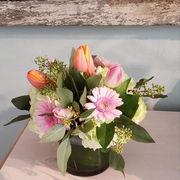 Pink gerbera daisies and tulips in a glass vase