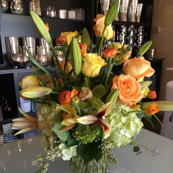 Mixed bouquet of orange and yellow flowers in a patterned vase