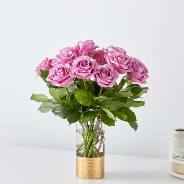 Pink roses arranged in a clear glass vase with a gold base