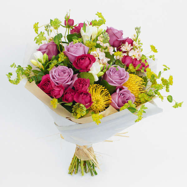 Bouquet of pink and lavender roses with yellow accent flowers
