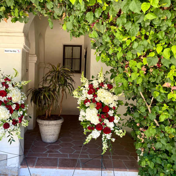 Two standing floral sprays with red and white flowers on metal easels