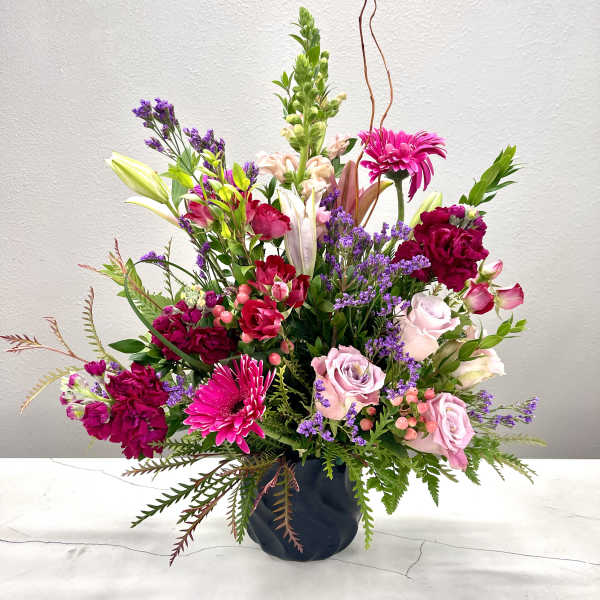 Mixed pink and purple flower arrangement in a dark vase