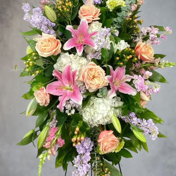 Standing floral spray with pink lilies, peach roses, and lavender blooms