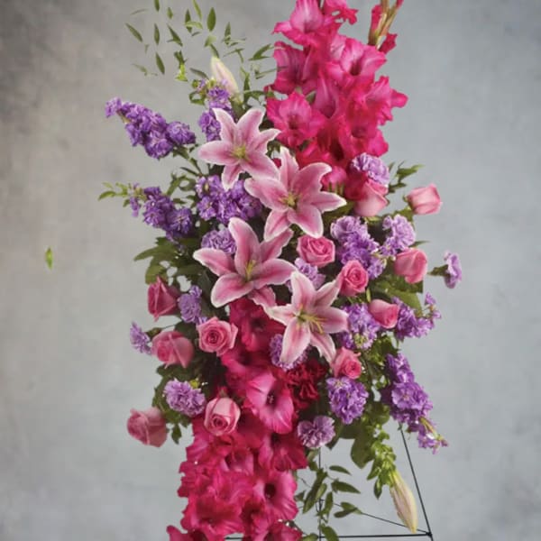 Tall arrangement of pink lilies, roses, and purple flowers